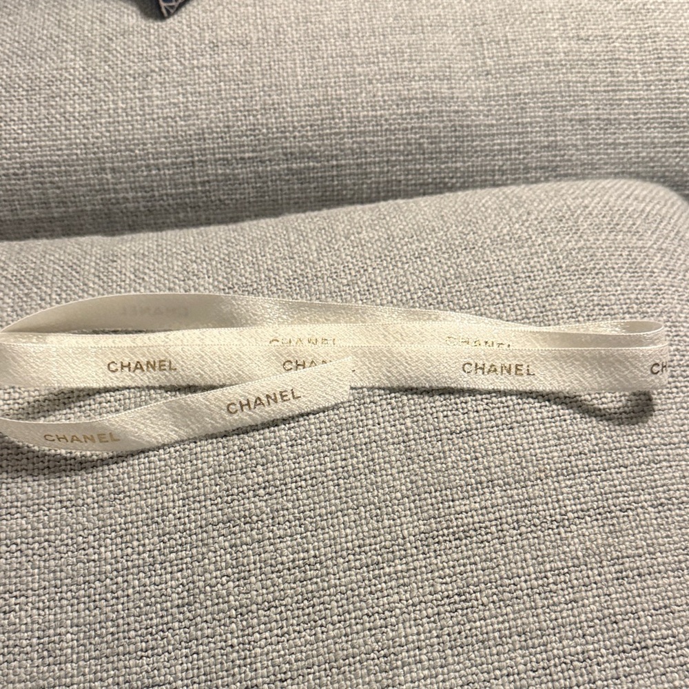 CHANEL Cream Logo Ribbon in white with gold lettering.